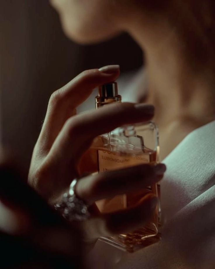 Jeune femme élégante s'aspergeant d'un parfum My Aura, une fragrance de luxe issue d'une fabrication minutieuse, inspirée des quatre saisons.