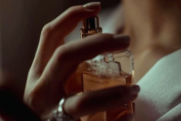 Jeune femme élégante s'aspergeant d'un parfum My Aura, une fragrance de luxe issue d'une fabrication minutieuse, inspirée des quatre saisons.