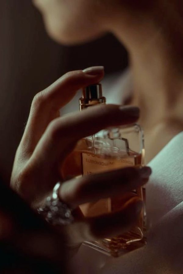 Jeune femme élégante s'aspergeant d'un parfum My Aura, une fragrance de luxe issue d'une fabrication minutieuse, inspirée des quatre saisons.